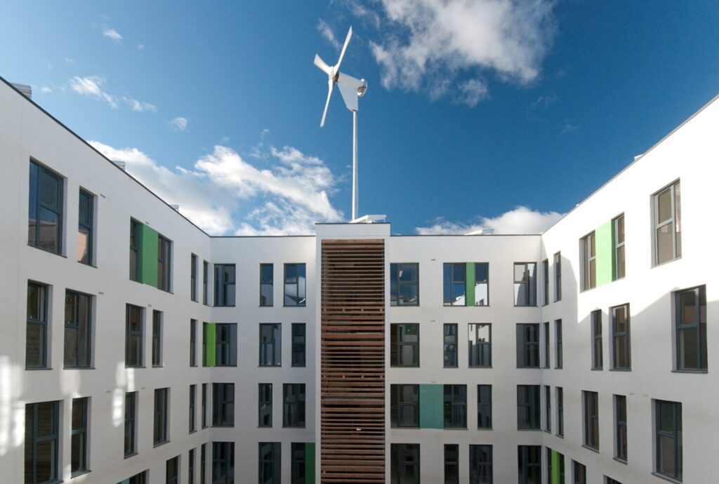 The Greenhouse, Leeds: white residential blocks around a courtyard, with a wind turbine on the roof