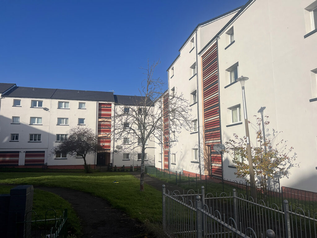 Dumbryden, Edinburgh: rendered residential blocks with red feature panels beside a green space