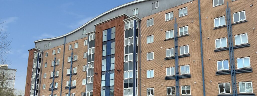 Firhill Court, Glasgow: eight-storey brick student accommodation block with a curved roofline under a blue sky