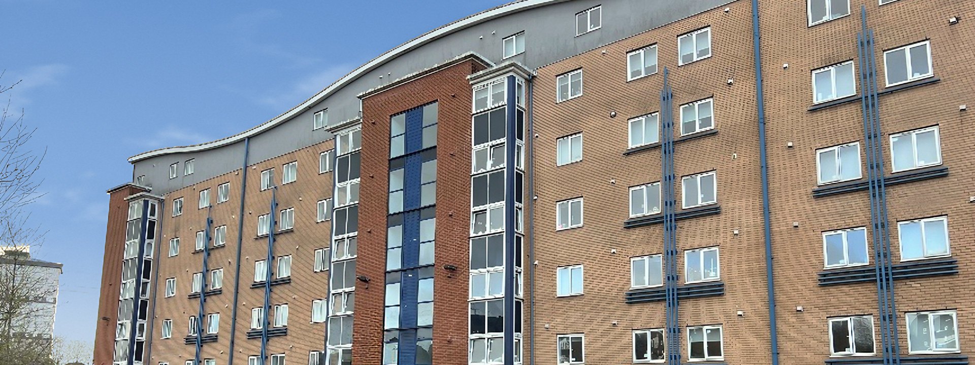 Firhill Court, Glasgow: eight-storey brick student accommodation block with a curved roofline under a blue sky